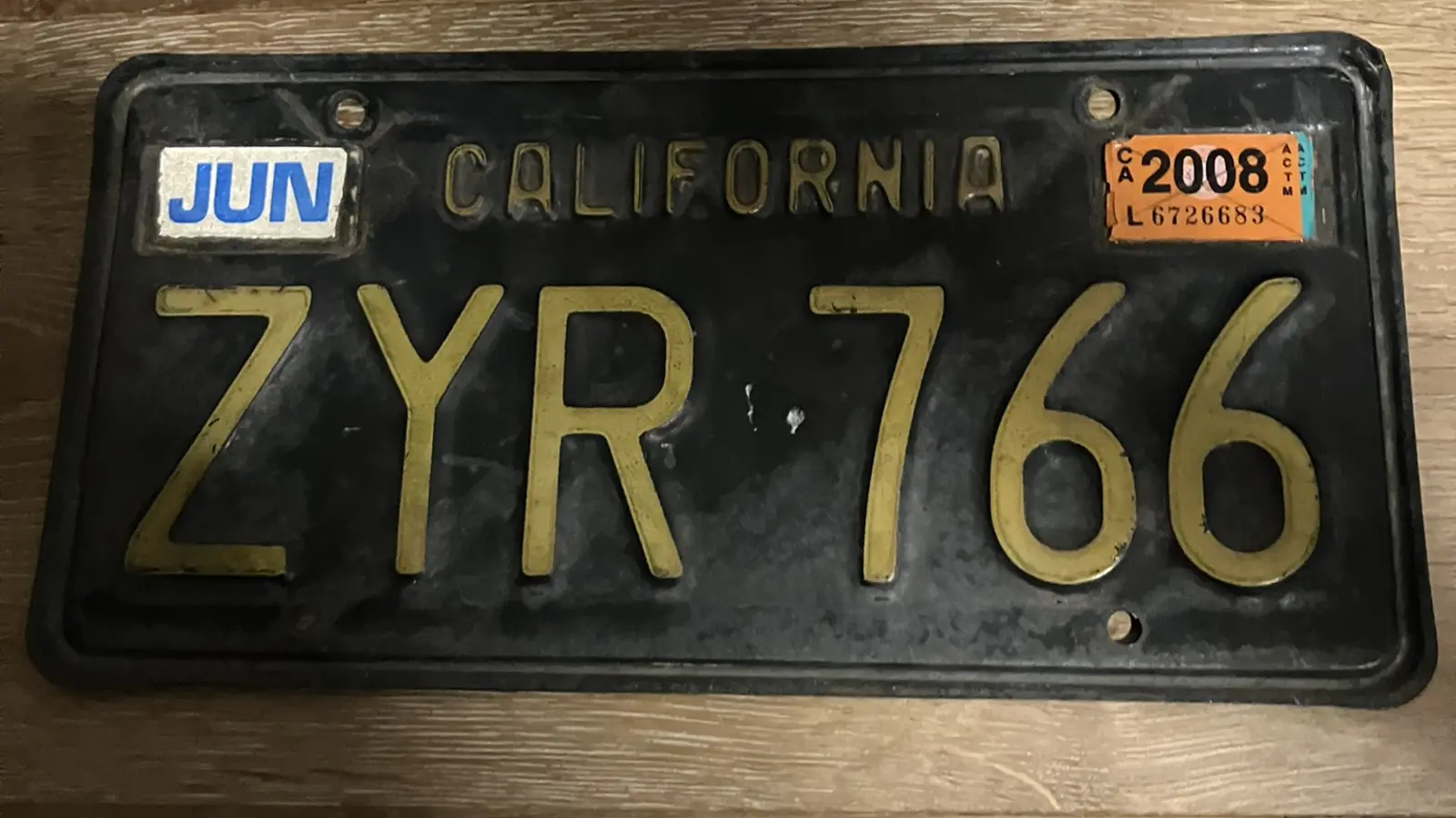 A black-and-gold 1970s California license plate with a 2008 registration sticker