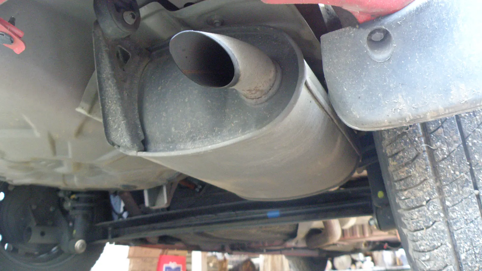 Close-up of a car exhaust pipe and muffler under the rear bumper
