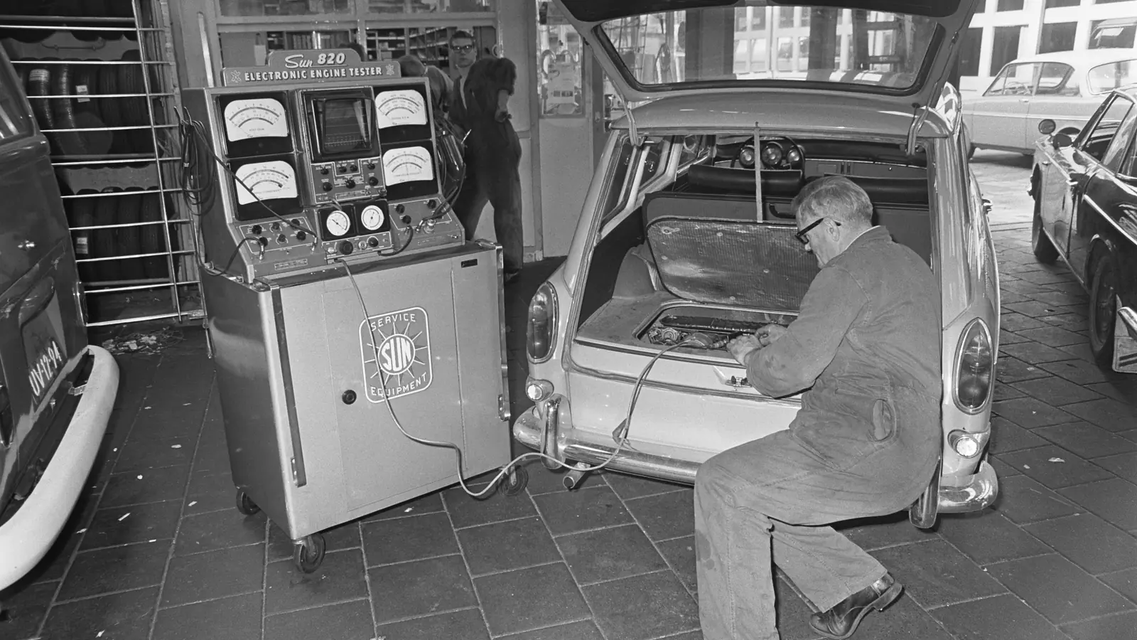 A mechanic tests a station wagon with an engine analyzer in a repair shop
